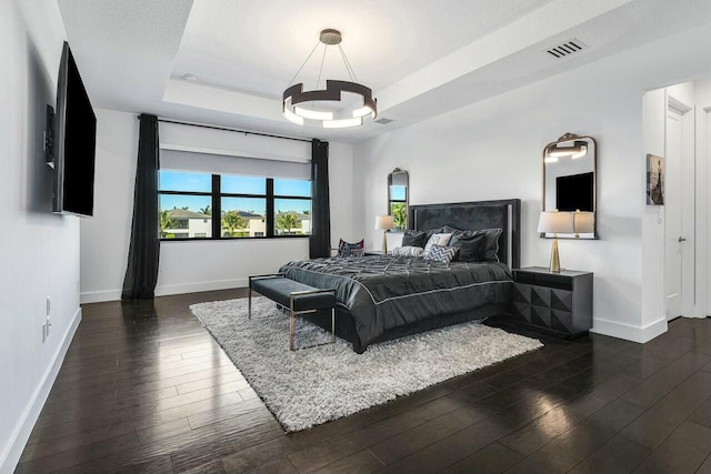 bedroom featuring a raised ceiling, dark wood-type flooring, and a textured ceiling