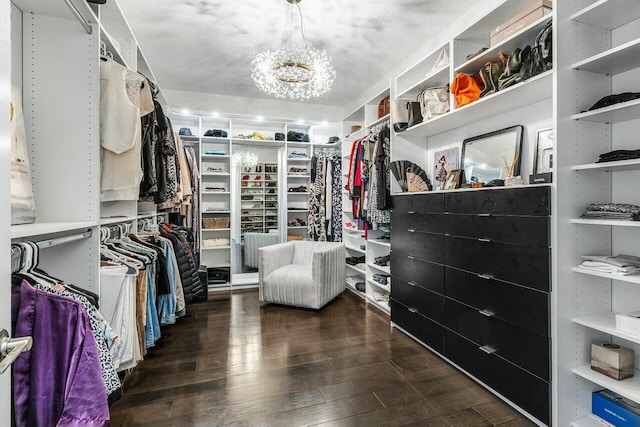 spacious closet with dark wood-type flooring and an inviting chandelier