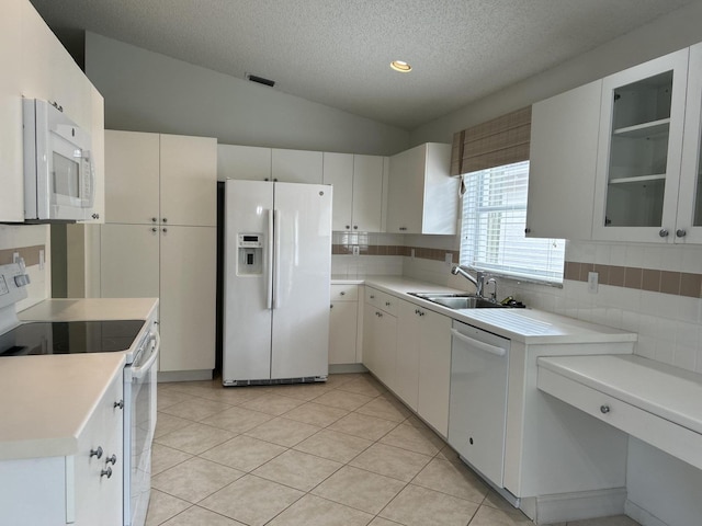 kitchen with sink, white cabinetry, a textured ceiling, vaulted ceiling, and white appliances