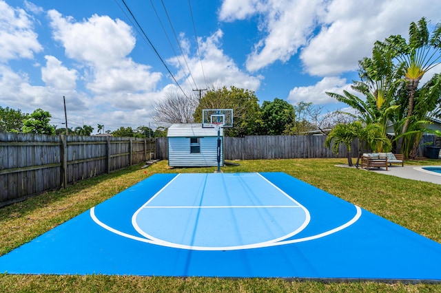 view of basketball court with a fenced backyard, a lawn, and a storage unit