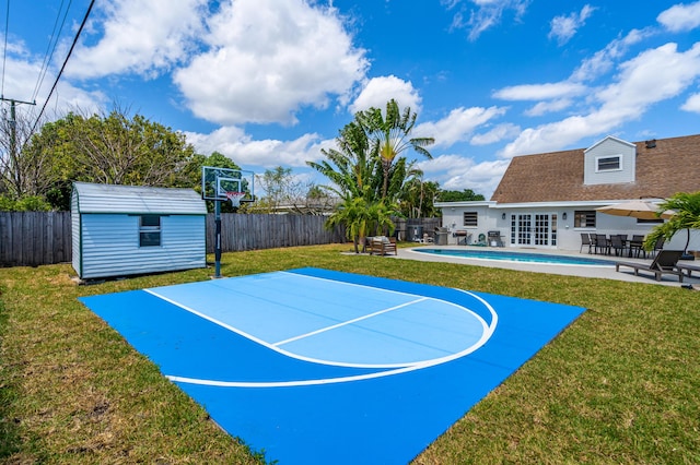 view of basketball court with a storage shed, a lawn, a fenced backyard, and a fenced in pool