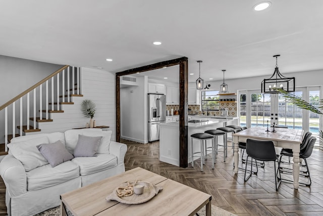 living area with wooden walls, recessed lighting, visible vents, and stairway