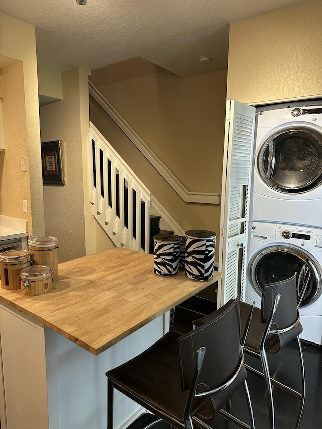 laundry area with stacked washing maching and dryer and a textured ceiling