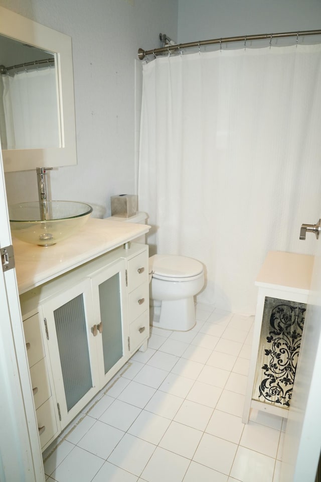 bathroom with toilet, vanity, and tile patterned floors