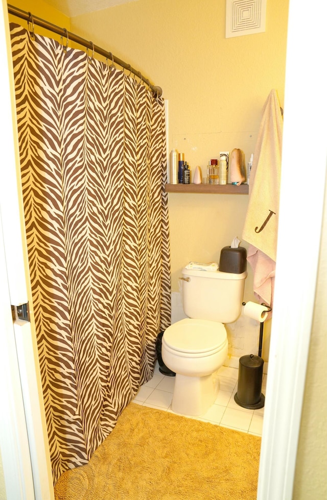 bathroom featuring walk in shower, tile patterned flooring, and toilet