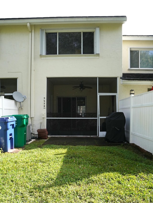 back of property with a sunroom, a yard, and central air condition unit