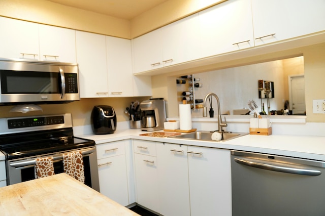 kitchen with appliances with stainless steel finishes, white cabinetry, and sink