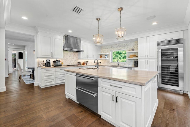 kitchen featuring white cabinetry, wine cooler, a center island with sink, and wall chimney range hood