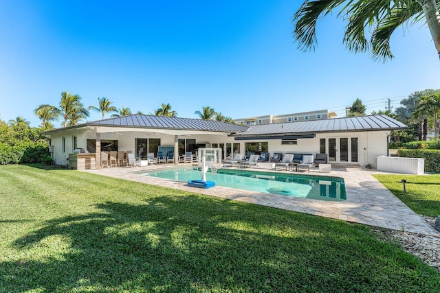 rear view of house with exterior bar, a patio area, and a lawn