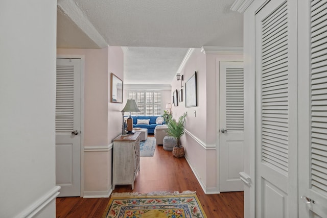 hallway featuring crown molding, a textured ceiling, and hardwood / wood-style flooring