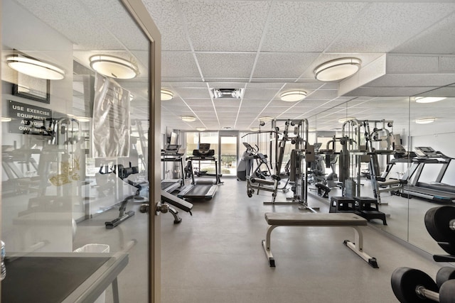 workout area featuring a paneled ceiling and a wall of windows