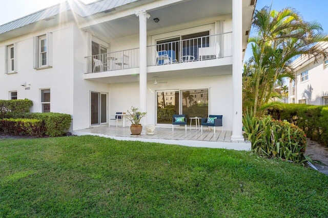 rear view of house with a yard, a patio, and a balcony