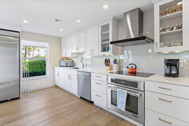 kitchen featuring white cabinetry, tasteful backsplash, wall chimney exhaust hood, and appliances with stainless steel finishes