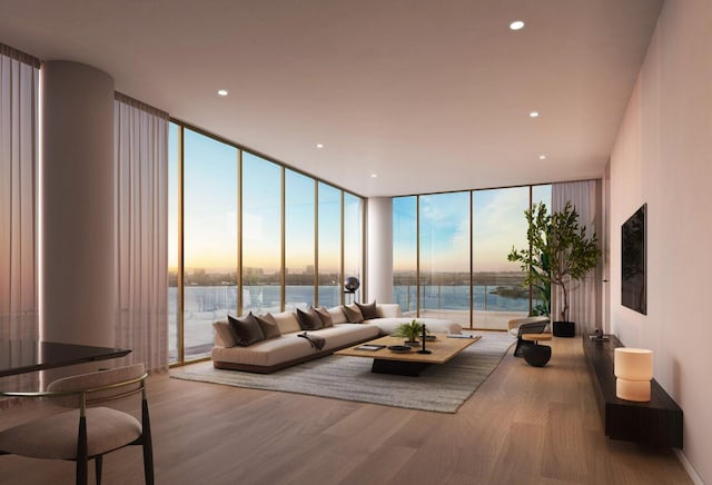 living room with expansive windows, plenty of natural light, a water view, and wood-type flooring