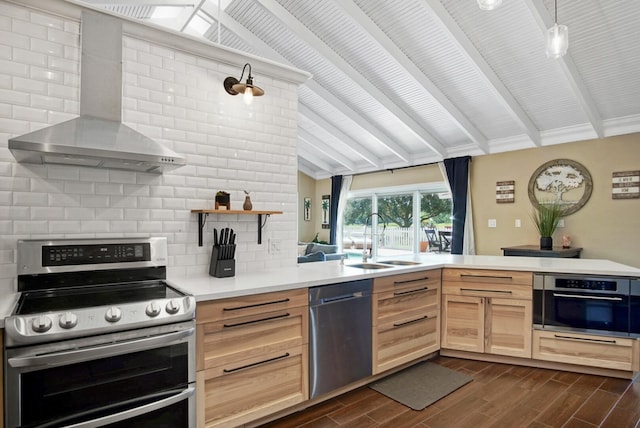 kitchen with light brown cabinets, lofted ceiling with beams, wall chimney range hood, sink, and appliances with stainless steel finishes