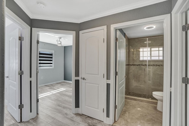 bathroom with wood-type flooring, ornamental molding, an enclosed shower, and toilet