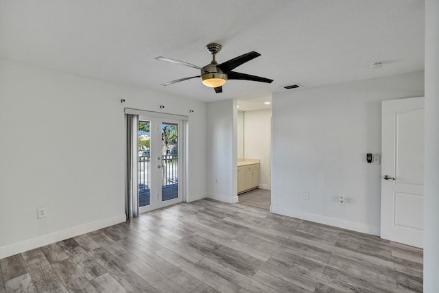 empty room with ceiling fan, light hardwood / wood-style flooring, and french doors