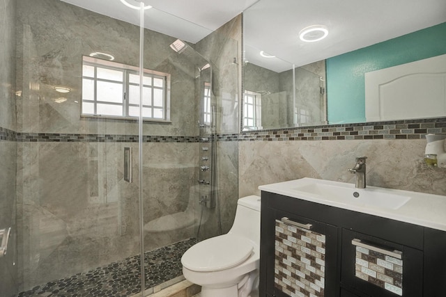 bathroom featuring vanity, decorative backsplash, toilet, tile walls, and a shower with shower door