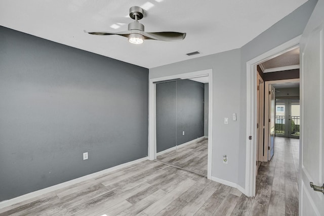 unfurnished bedroom with ceiling fan, a closet, light hardwood / wood-style floors, and ornamental molding