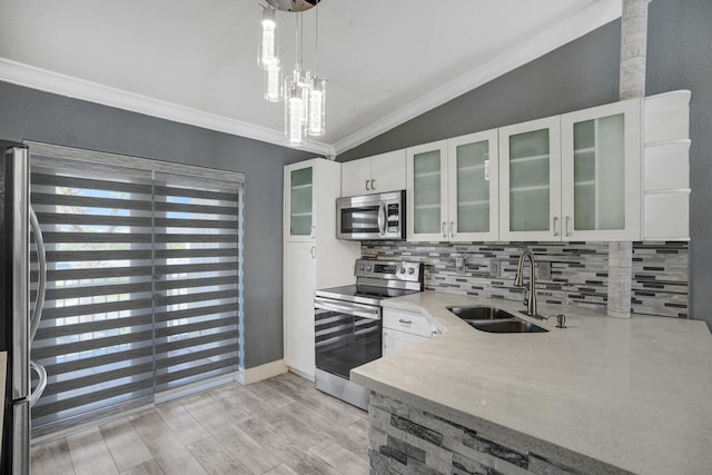 kitchen with appliances with stainless steel finishes, sink, decorative light fixtures, white cabinets, and lofted ceiling