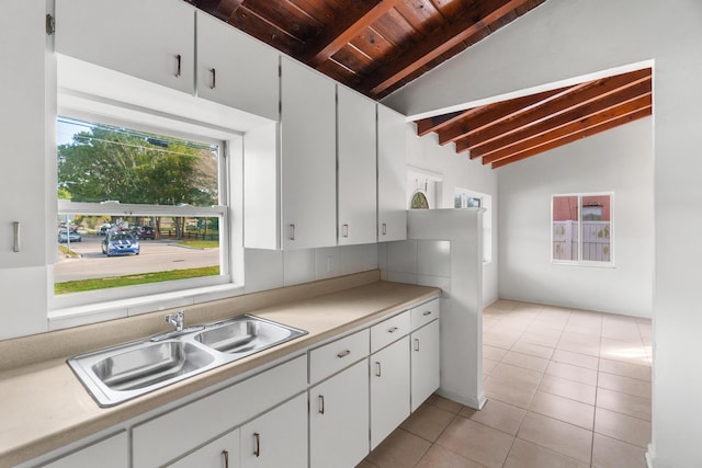 kitchen featuring white cabinetry, sink, lofted ceiling with beams, light tile patterned flooring, and wood ceiling