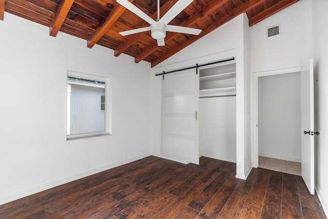 unfurnished bedroom featuring ceiling fan, dark wood-type flooring, a barn door, vaulted ceiling with beams, and a closet