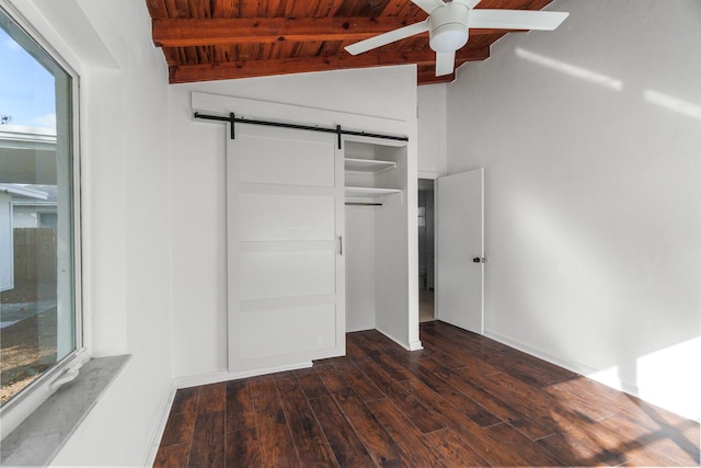 unfurnished bedroom with wooden ceiling, lofted ceiling with beams, ceiling fan, a barn door, and dark hardwood / wood-style flooring