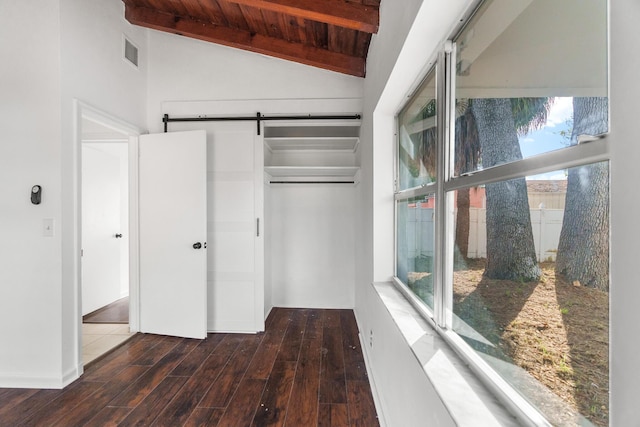 unfurnished bedroom featuring a barn door, lofted ceiling with beams, wooden ceiling, and multiple windows