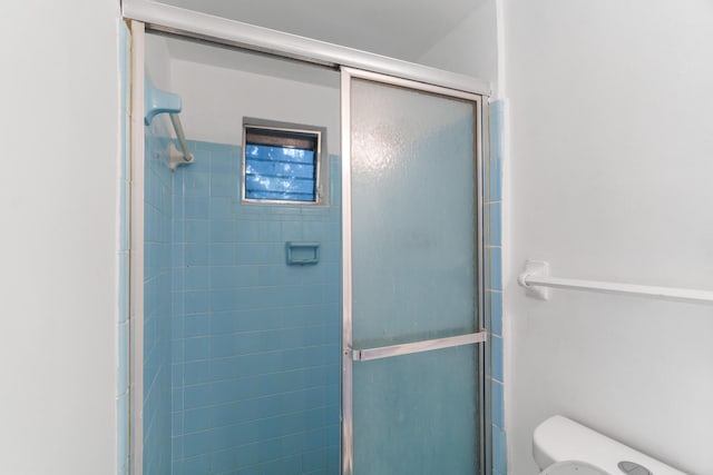 bathroom with toilet and a shower with shower door