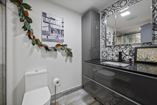 bathroom featuring walk in shower, backsplash, wood-type flooring, toilet, and vanity