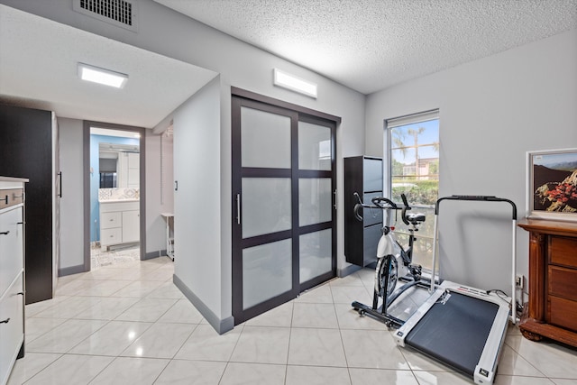 workout room with light tile patterned flooring and a textured ceiling