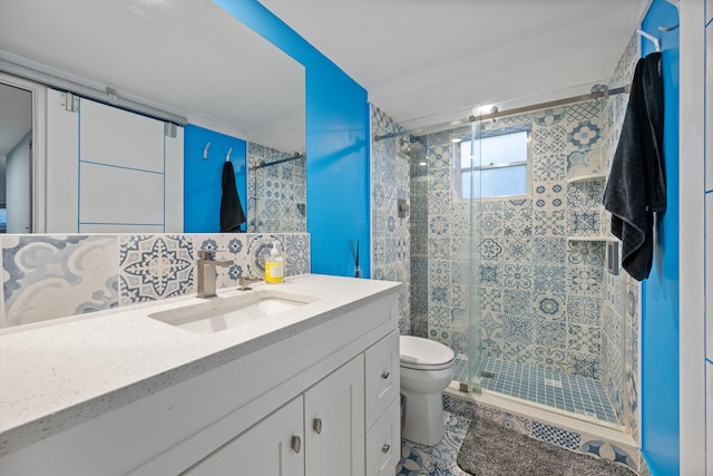 bathroom with vanity, a shower with door, tile patterned flooring, decorative backsplash, and toilet