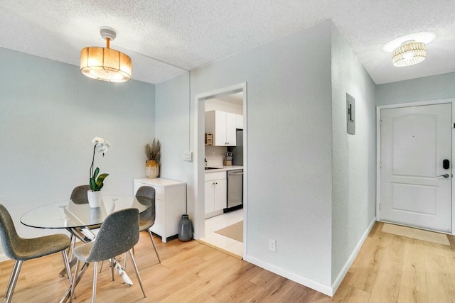 dining area with light wood-type flooring, a textured ceiling, and electric panel