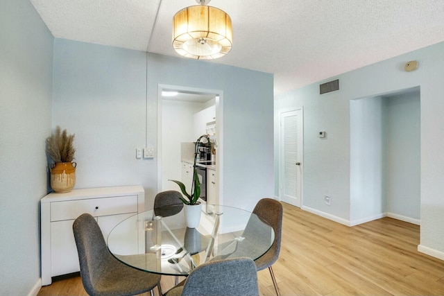 dining space with a textured ceiling and light wood-type flooring