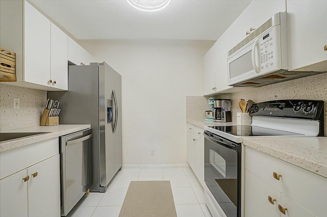 kitchen with backsplash, light tile patterned floors, white cabinets, and white appliances