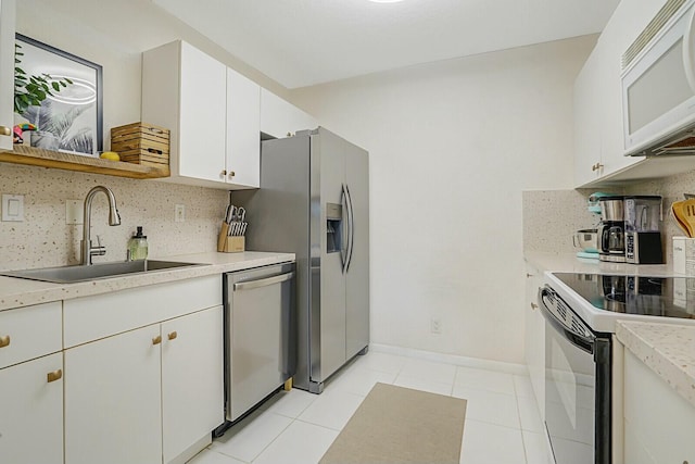 kitchen with sink, light tile patterned floors, appliances with stainless steel finishes, tasteful backsplash, and white cabinetry