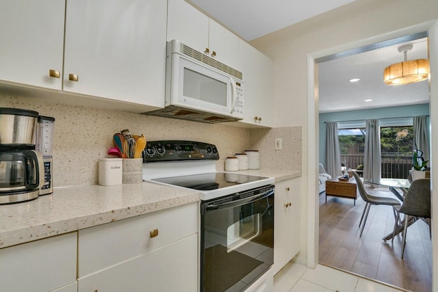 kitchen featuring tasteful backsplash, white appliances, light tile patterned floors, decorative light fixtures, and white cabinets