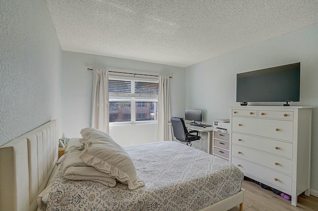 bedroom with radiator heating unit, a textured ceiling, and light hardwood / wood-style flooring