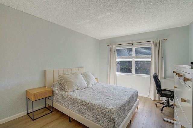 bedroom with light hardwood / wood-style floors and a textured ceiling