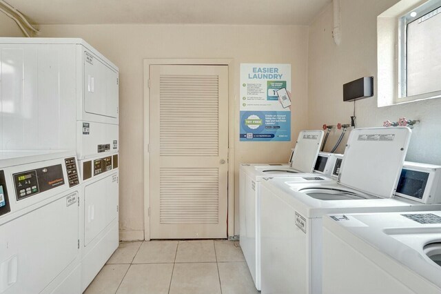 laundry room with light tile patterned flooring, stacked washer and dryer, and washing machine and clothes dryer