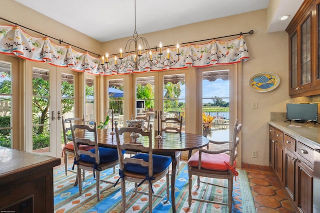 dining space with dark tile patterned flooring, a chandelier, and french doors