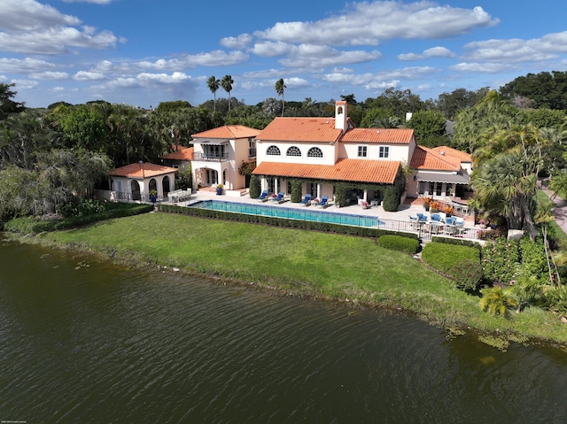 rear view of house with a water view, a balcony, a yard, and a patio area