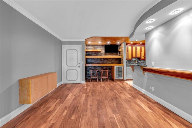 interior space featuring beverage cooler, tasteful backsplash, built in features, ornamental molding, and light wood-type flooring