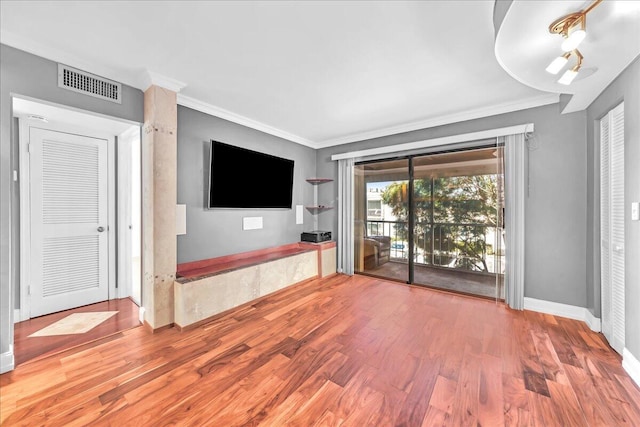 unfurnished living room with hardwood / wood-style floors and crown molding