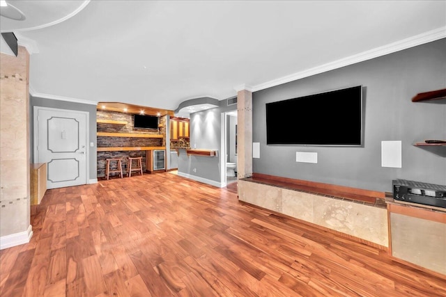 unfurnished living room featuring light hardwood / wood-style flooring, beverage cooler, and ornamental molding