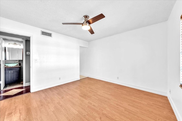 spare room with ceiling fan, a textured ceiling, and light wood-type flooring