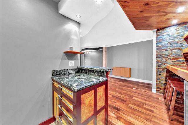 kitchen featuring dark stone countertops, wood ceiling, dark hardwood / wood-style floors, and ornamental molding