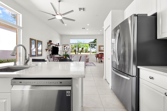 kitchen with light stone countertops, sink, light tile patterned floors, white cabinets, and appliances with stainless steel finishes