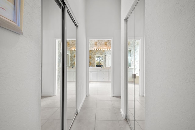 hallway with a towering ceiling and light tile patterned floors