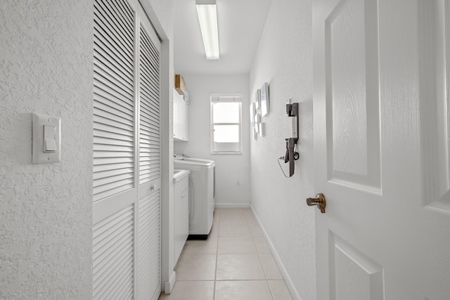 clothes washing area with cabinets, separate washer and dryer, and light tile patterned floors